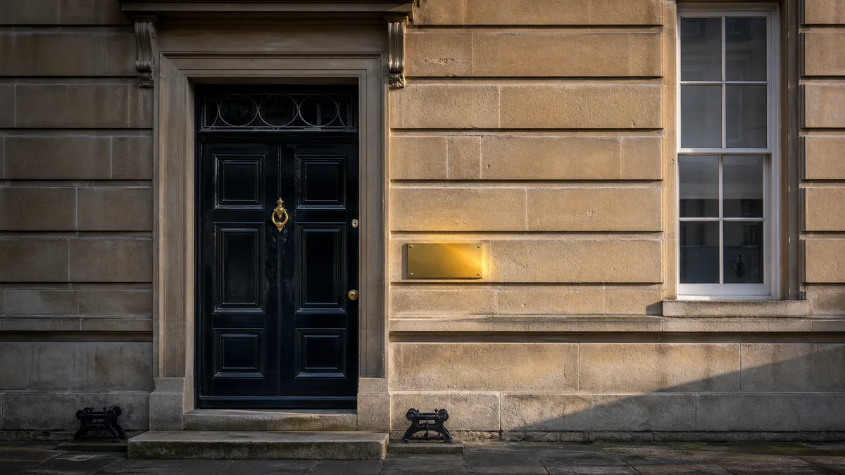 Exterior of a Georgian UK solicitors office with a brass nameplate in morning light